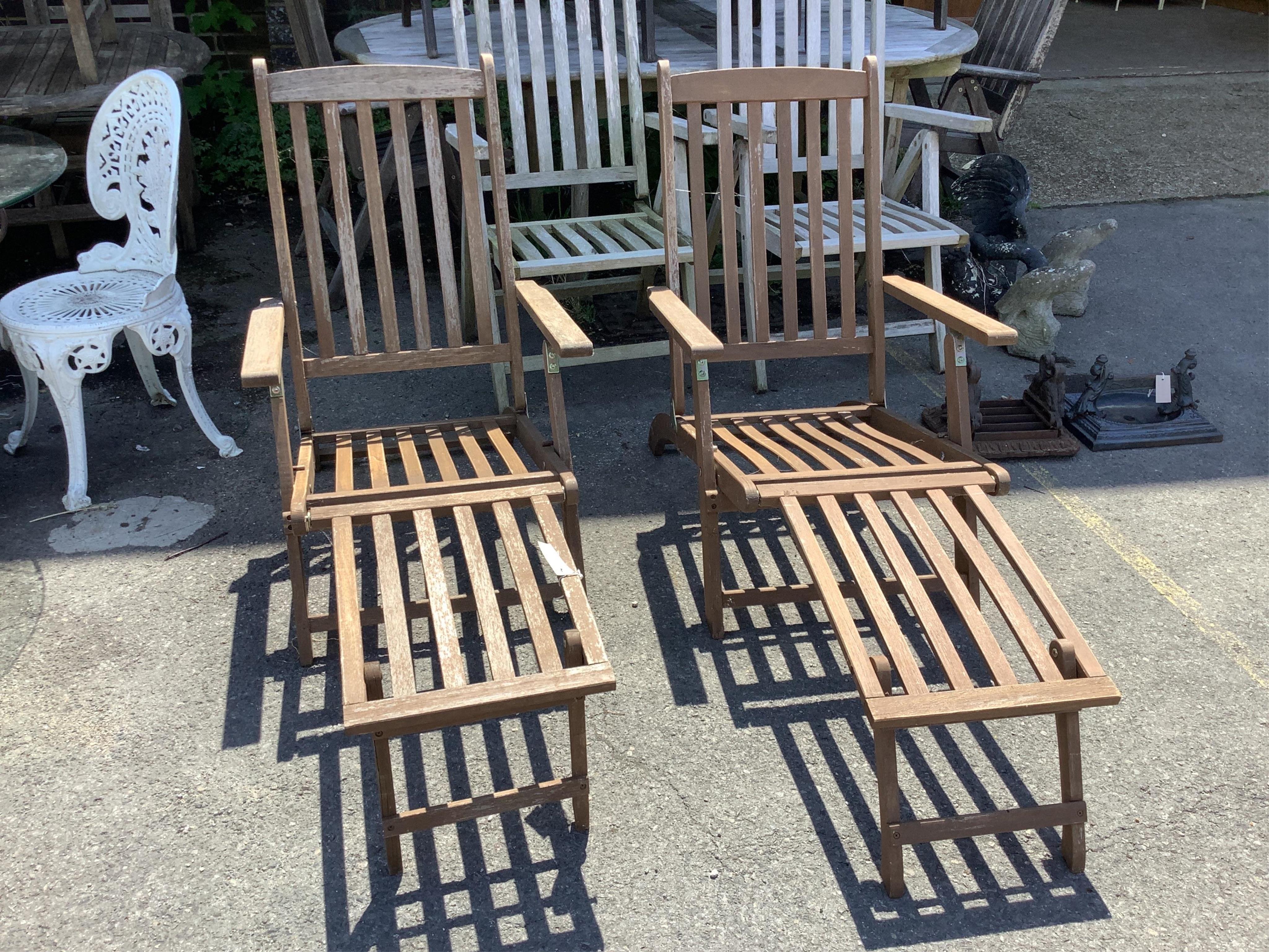 A pair of stained teak garden steamer chairs, width 59cm, height 97cm. Condition - fair